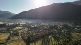 Sun rising from behind the mountain hill of picturesque Italian countryside, morning mist covering small rural village at the hillside, panoramic view of fields with growing cypresses, olive trees - Powered by Shutterstock - Get 15% off with code: PIKWIZARD15