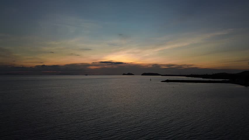 Aerial drone footage of Baan Tai Pier on Koh Phangan island in Thailand during a golden sunset, with calm ocean waters and distant islands visible in the background.
