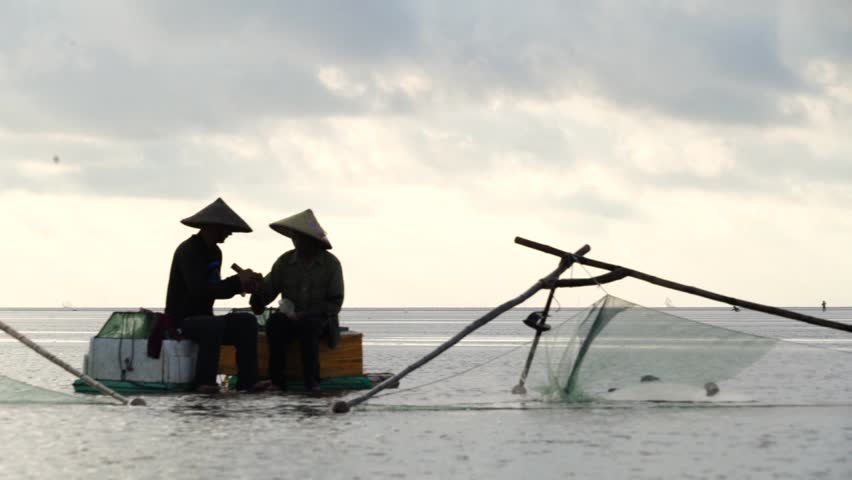 Fishermen stand on bamboo sticks and use nets to catch fish in the morning at Infinity Beach in Hanoi, Vietnam, on August 12, 2025.