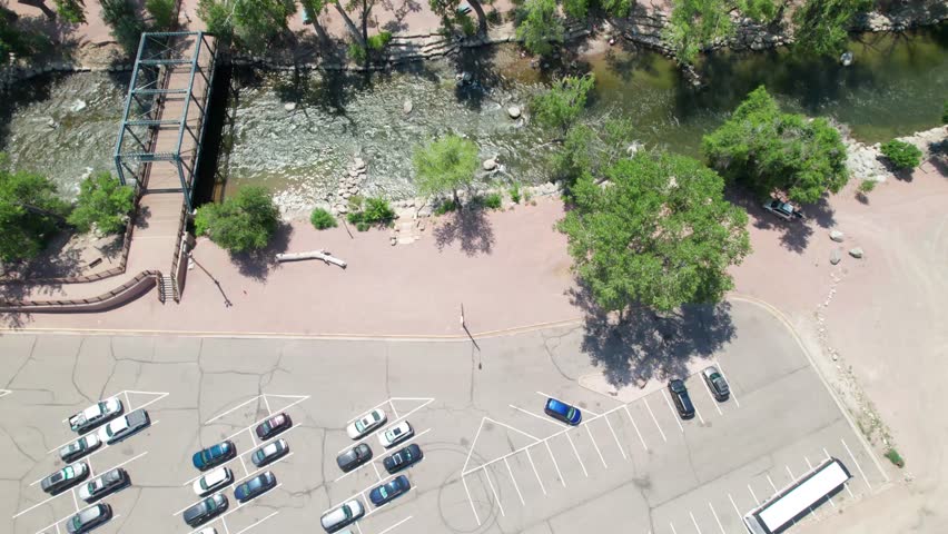 Aerial video of the Arkansas River in Canon City, Colorado. Camera is looking straight down and flies over a parking lot and the river. A bridge can be seen to the left side of the video.