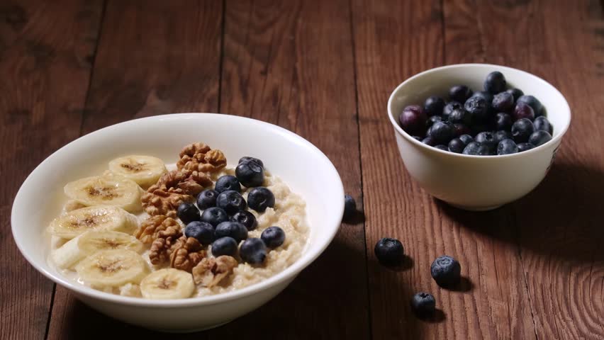 Oatmeal with blueberries, banana and nuts. A spoon scoops up the porridge. Healthy breakfast.