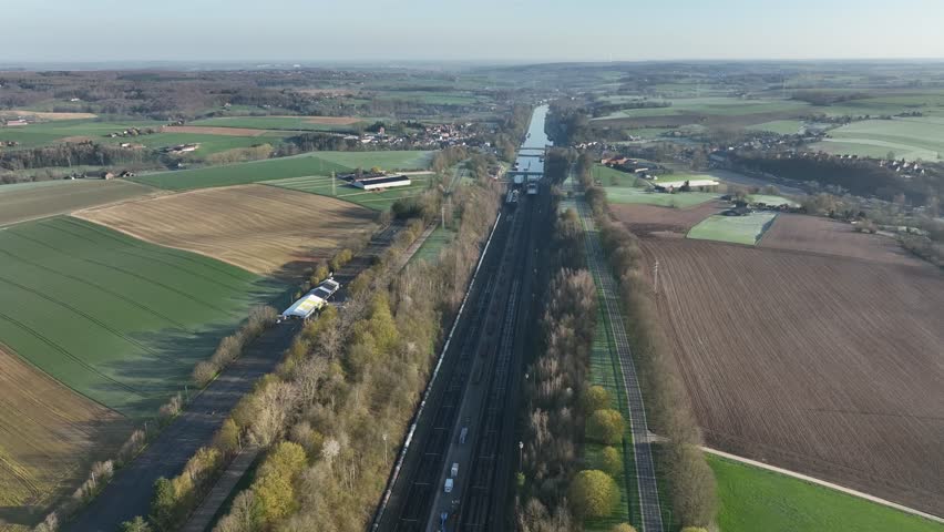 Drone zoom in towards the Ronquieres ship lift and canal in Belgium, surrounded by countryside fields under sunny daylight.