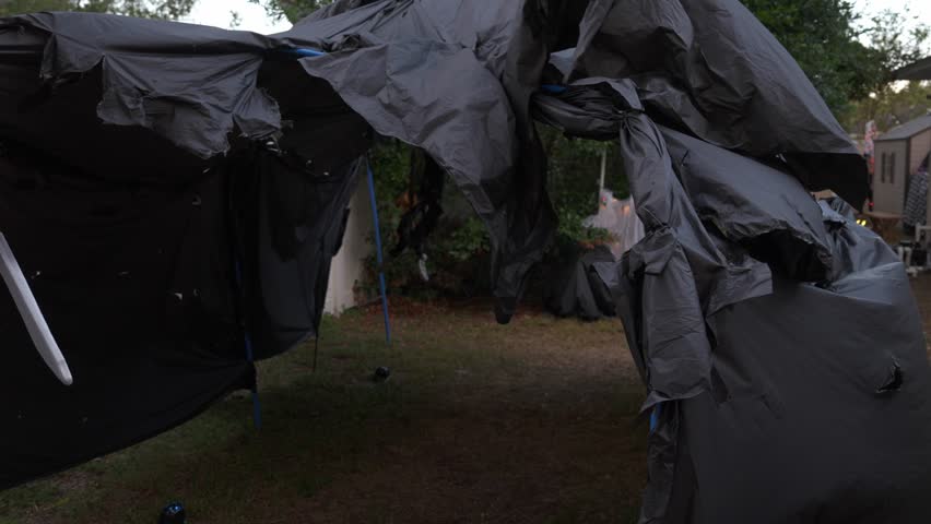 Backyard Halloween bar: skeleton bartender with skull decor, pumpkins, orange glow, and a jack-o-lantern near the shed.