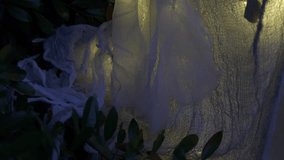 Close-up of a white Halloween ghost with red glowing eyes at night. Gauze fabric and warm lights create a spooky outdoor yard decoration. - Powered by Shutterstock - Get 15% off with code: PIKWIZARD15