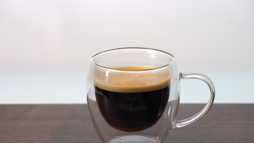 Adding 3 wooden spoons of brown sugar to hot black coffee in double wall clear glass cup, creating cozy inviting morning atmosphere, minimal style, aromatic fresh drink, energy, transparent modern