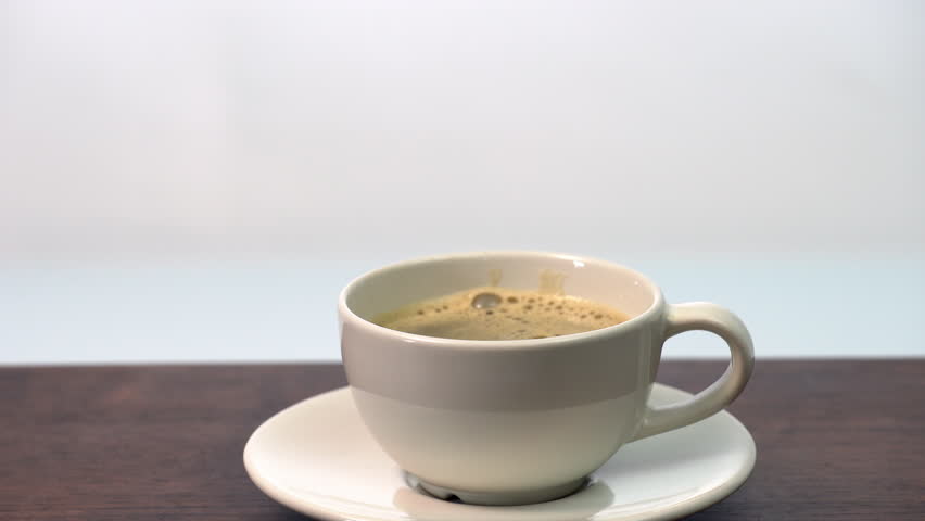 Adding coffee with 3 organic sugar cubes in white ceramic cup hot beverage on wooden table, minimal style morning drink, caffeine boost, cozy relaxation, warm atmosphere, simple calm refreshment