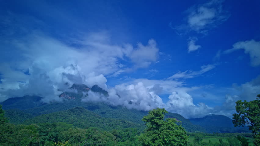 Time lapse White clouds in blue sky cover the peak of Chiang Dao Mountain. The clouds on the mountaintop kept changing shape. Misty Mountain Under Overcast Sky

