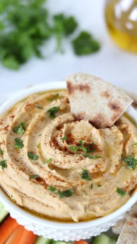 Hand is dipping pita bread in homemade lentil hummus. Vertical video. Close-up.