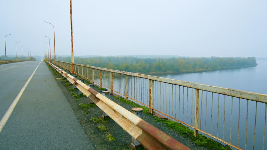 The Paryshivskyi Bridge spanning the Pripyat River, shrouded in a misty, atmospheric autumn fog. The scene captures the serene and somewhat haunting beauty of the Polesia region, with the river flowin