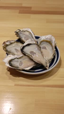 Vertical shot: Five delicious, juicy oysters on a dish.