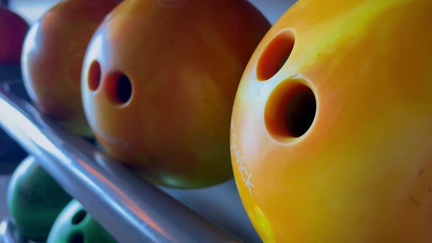 Bowling balls lined up on a rack, ready for play. Concept of recreational bowling, leisure time, and waiting for the next strike