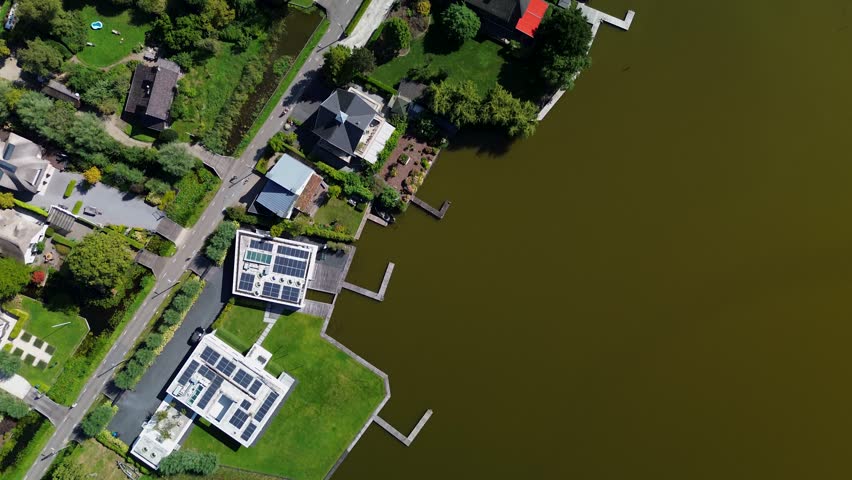 Aerial view of a lakeside residential area with modern and traditional homes, tree-lined roads, and private docks. Calm water and small islands enhance the serene, nature-integrated setting.