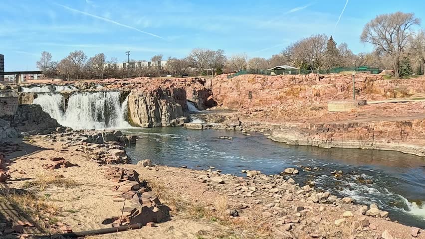 Waterfalls at Sioux Falls, Falls Park, with Red Quartzite Rocks, Blue Sky, and Sunlit Landscape, South Dakota