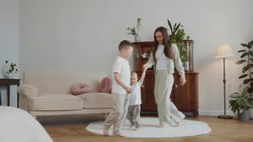 Wide shot shows mother with her sons aged seven and two running and dancing playfully on a white carpet in a bright room. A lifestyle moment full of movement, joy, and everyday happiness. 4k footage - Powered by Shutterstock - Get 15% off with code: PIKWIZARD15