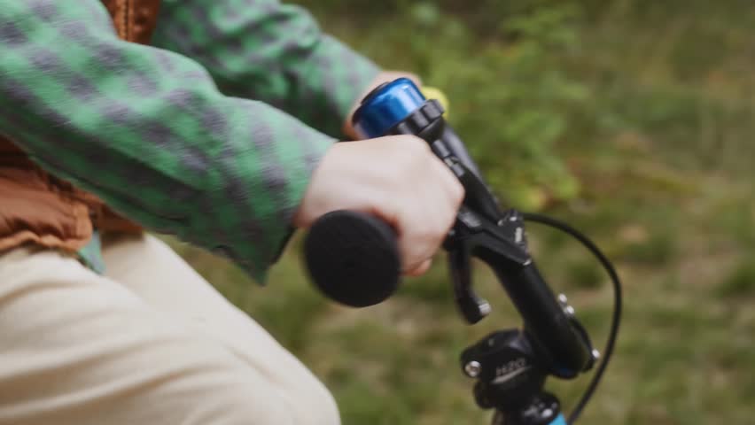 Close detail shot shows boy in green shirt gripping handlebar while riding Symbol of control self confidence and independence in growing up. High quality 4k footage