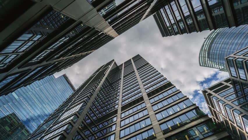 Low angle hyperlapse motion time-lapse downtown high-rise glass skyscrapers on sunny day, financial district looking up tall modern architecture office buildings city street, blue sky white clouds