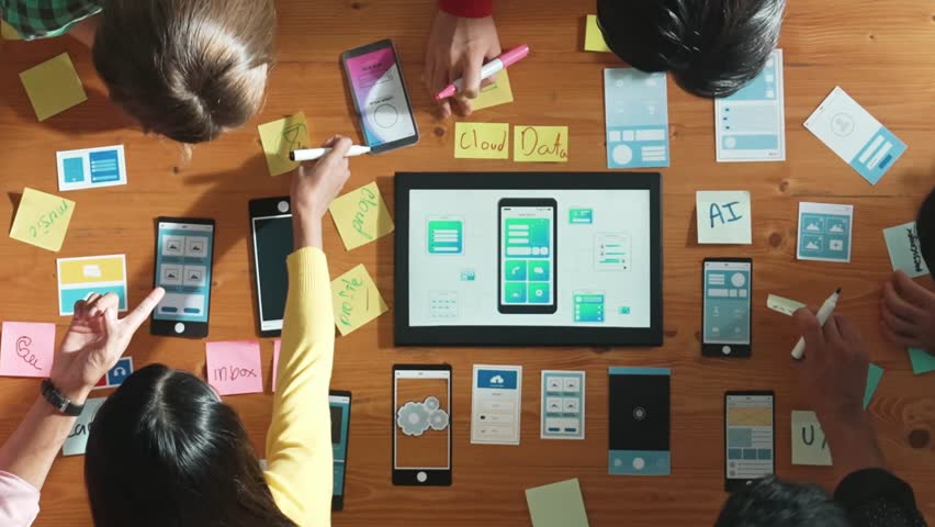 Top view of developer team working together to write idea about Ux ui design on colorful sticky note. Group of programmer looking at wireframe prototype at tablet and designing software. Convocation.