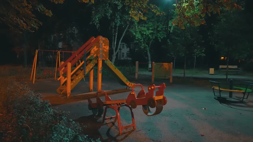 Empty Children Playground at Night with Slide Swing and Merry-Go-Round | Dark Evening Park Recreation Area | Urban Neighborhood Family Entertainment Zone