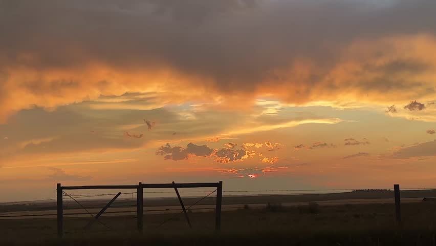 Agricultural field at sunset with glowing sky, dramatic clouds, and wide prairie view, highlighting rural life, scenic beauty, and open countryside atmosphere in Alberta, Canada.