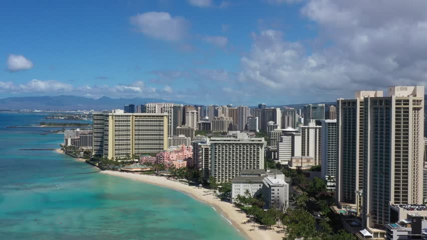 Aerial view of a modern coastal city skyline with tall buildings along the beach.