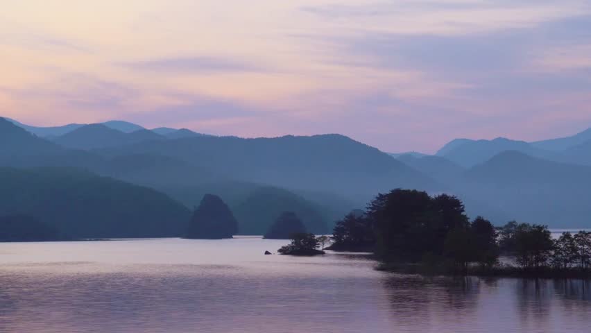 Serene lake landscape with mountains and islands at dusk