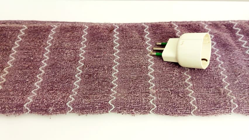 Close-up of adapter resting on zigzag-patterned towel. Textures pop-soft weave meets hard plastic. Ideal for tech setups, product demos, or cozy contrast visuals