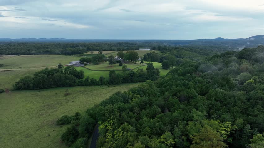 Beautiful green landscape with old historic building during cloudy day in America. Aerial wide shot. Rural area with fields and forest.