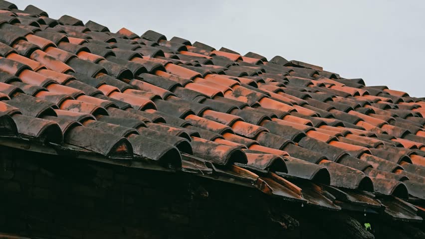 Rain falling on rustic clay roof tiles, capturing a moody monsoon atmosphere and traditional village charm - Powered by Shutterstock - Get 15% off with code: PIKWIZARD15