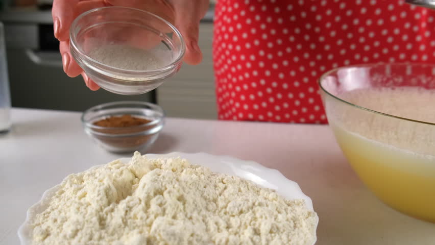 Baker woman adding baking powder to flour in white bowl cooking on kitchen. Pastry chef hands preparing bakery mixing ingredients. Culinary skills, cuisine, homemade domestic recipe food dish.