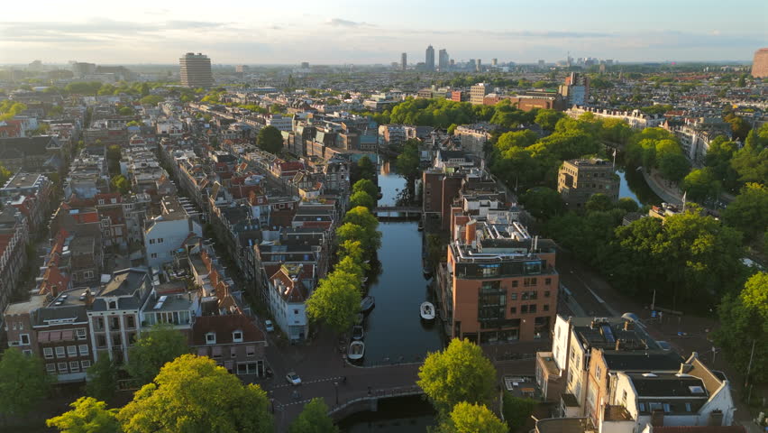 Stunning aerial view of Amsterdam highlights its iconic canals, lush greenery, and historic architecture, creating a vibrant urban landscape that invites exploration and adventure