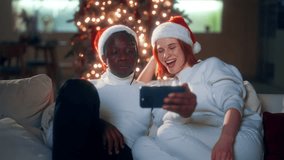 Merry Christmas and happy new year, biracial couple relaxing at home in night. Joyful young woman and man surfing internet by smartphone, modern technology and traditional celebration winter fest - Powered by Shutterstock - Get 15% off with code: PIKWIZARD15