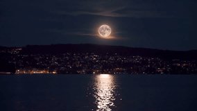 Cinemagraph of full moon over Lake Zurich at night with city lights reflecting on moving water - Powered by Shutterstock - Get 15% off with code: PIKWIZARD15