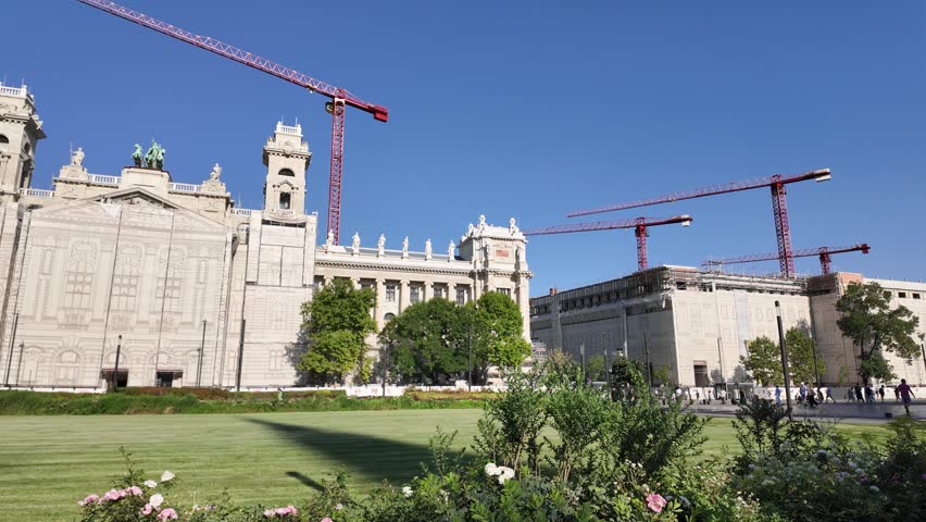 Panoramic shot of the Palace of Justice in Budapest, Hungary, capturing active renovation work with towering cranes around its grand neoclassical structure