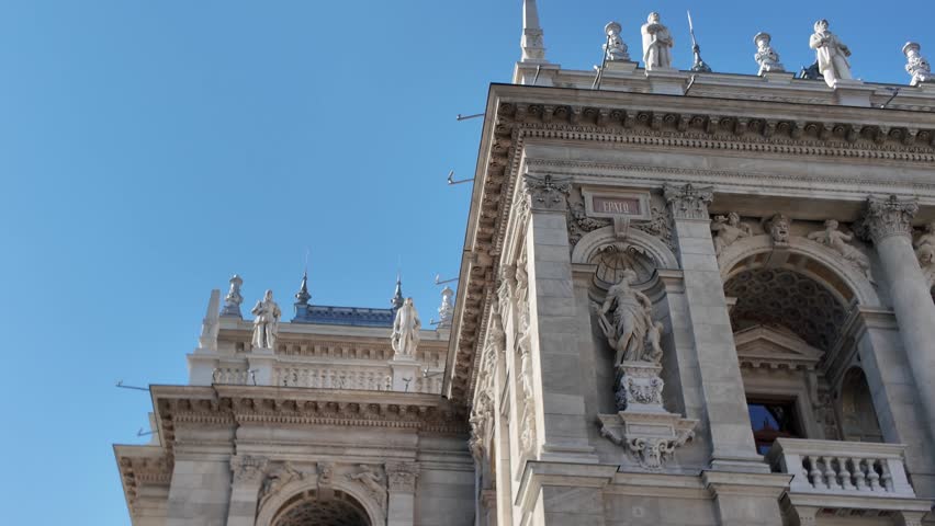 Opera house front façade in Budapest, showcasing intricate arches, sculpted statues, and classical architectural details