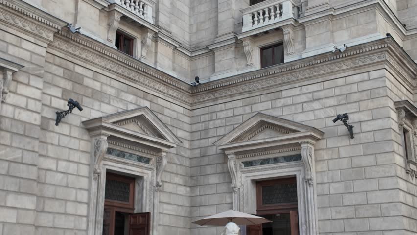 Smooth upward pan of the Hungarian State Opera in Budapest, revealing the elegant side façade with its ornate rooftop statues and neo-Renaissance details