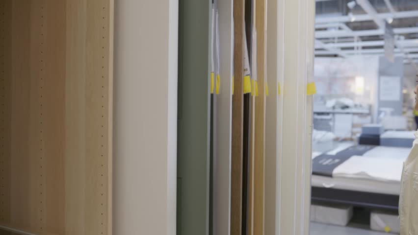 Woman choosing from different door styles in interior showroom, focusing on design aesthetics and home improvement, showing renovation choices, surface textures and architectural inspiration