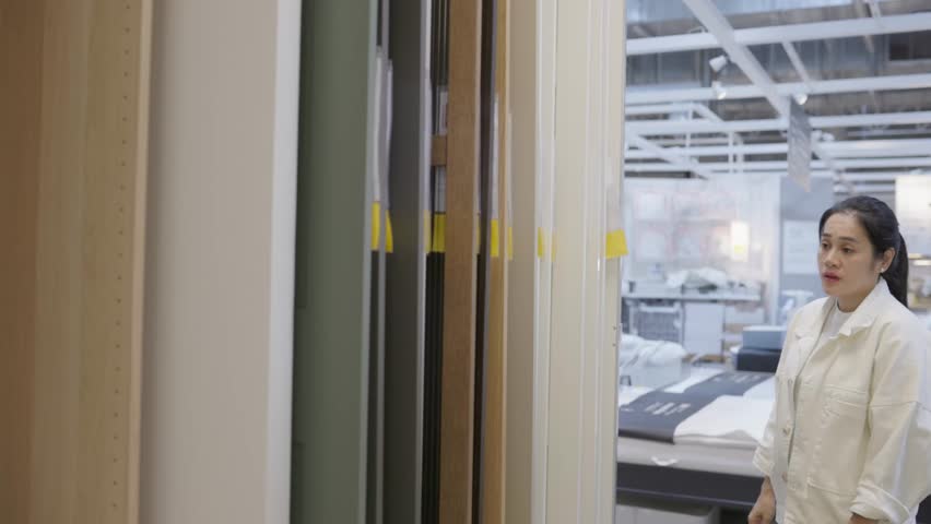 Woman choosing from different door styles in interior showroom, focusing on design aesthetics and home improvement, showing renovation choices, surface textures and architectural inspiration