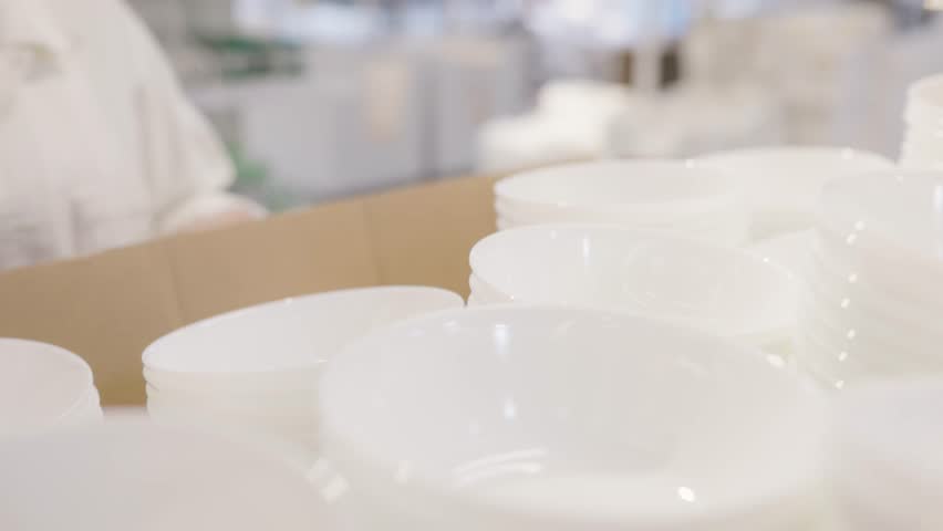 Customer selecting white porcelain bowl from organized stack in retail store, everyday decision highlighting clean ceramic tableware, lifestyle choice and kitchen essentials
