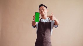 Barista in apron points to green screen phone perfect for mockup or app design - Powered by Shutterstock - Get 15% off with code: PIKWIZARD15