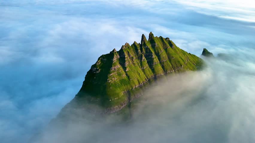 Towering above the enchanting sea, Drangarnir Cliff presents a stunning sight in the Faroe Islands. Surrounded by ethereal mist and rugged terrain, this natural wonder beckons adventurers.