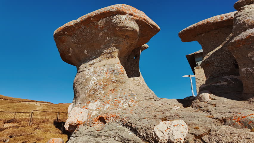 Mushroom shaped and antropomorphic rock formations in a beautiful mountain range, displaying weathered stone columns, rounded caps, and curious silhouettes, under open sky across rugged terrain