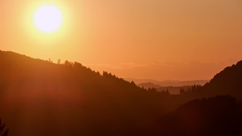 Timelapse of a dramatic sunset over a mountain ridge with vibrant clouds