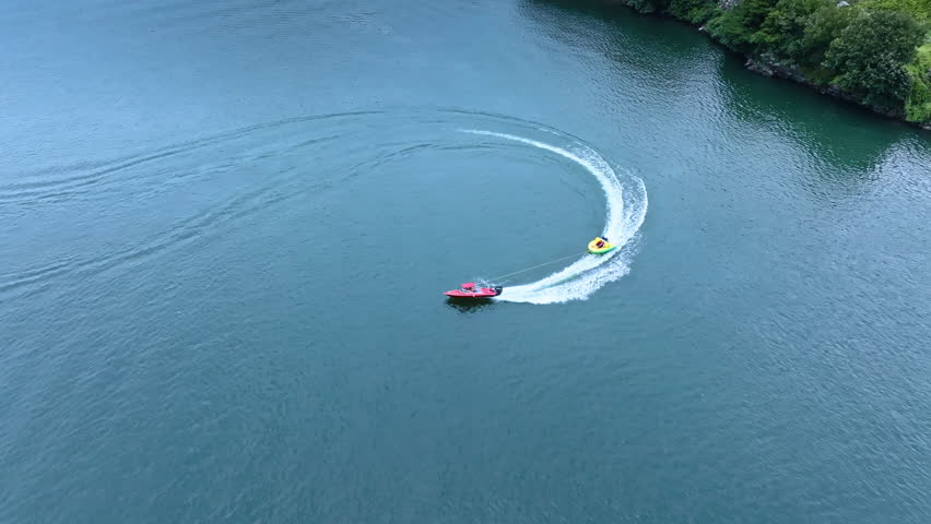 Drone Aerial View of Speedboat Towing Banana Boat on Lake