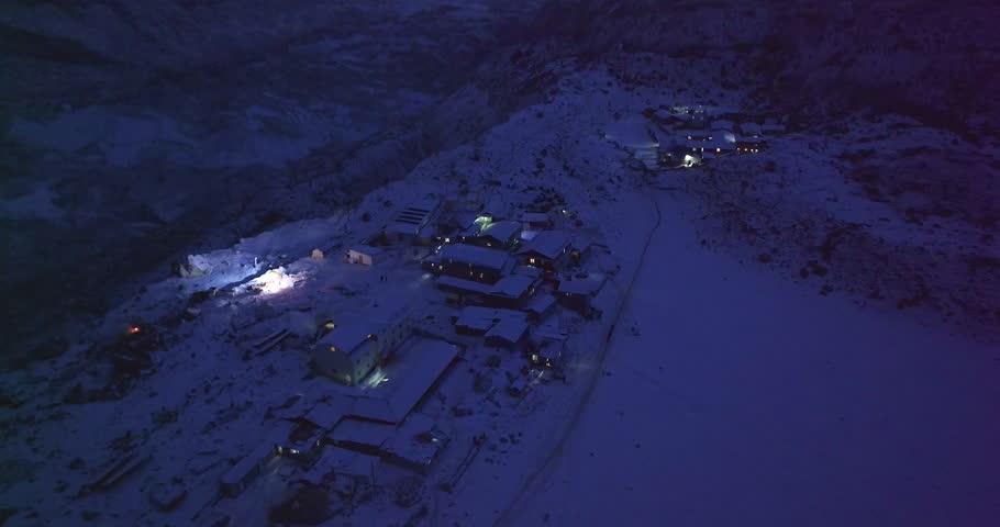 Night-time drone shot over Khumbu Glacier and Gorakshep on Everest Base Camp trek, Sagarmatha, Nepal. High-altitude Sherpa village housing glows under Himalayan peaks, unique tourism and climbing spot