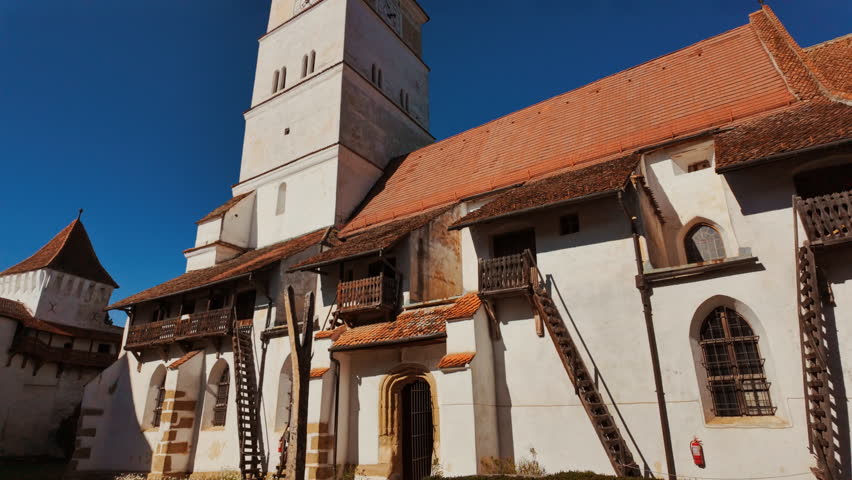Harman Fortified Church, Harman, Transylvania, Romania, combines a white walled church, defensive ring, and robust tower, enclosing a calm courtyard that reflects centuries of community life
