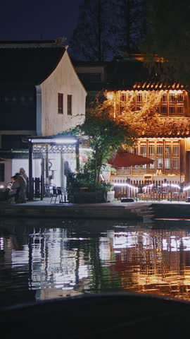 Zhujiajiao, Shanghai, China. idyllic night scene features buildings adorned with lanterns along the riverbank, reflecting beautifully on the water and evoking a sense of peace and charm.