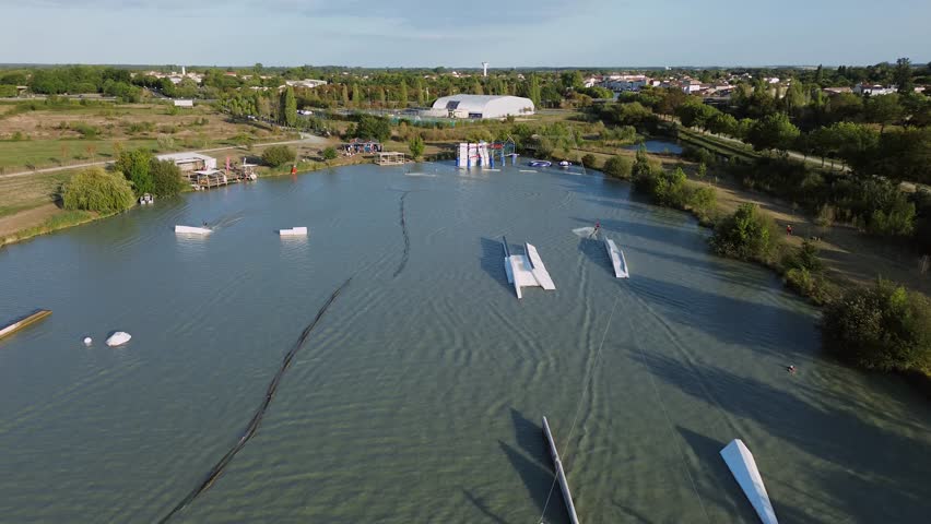 From above, the drone reveals Lac de Saujon’s téléski station with riders in action, contrasting the calm natural lake with the energy of watersports.