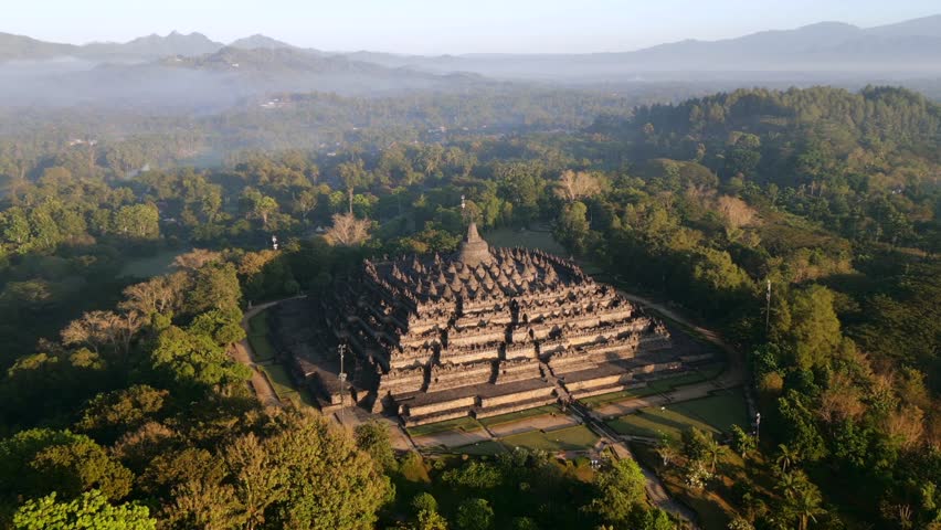 Aerial view of Borobudur Temple in Central Java, Indonesia. Ancient Buddhist monument at sunrise, surrounded by tropical jungle. UNESCO World Heritage Site, culture, history, and travel themes.