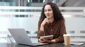 Businesswoman watching video call online conference taking notes looking at laptop computer screen sitting at workplace in office. Female employee listening remote business training, course or seminar - Powered by Shutterstock - Get 15% off with code: PIKWIZARD15