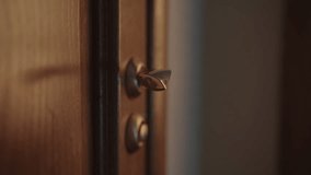 Male hand grasps and turns golden handle of wooden door, poised to enter or exit softly lit hotel room, creating sense of anticipation and transition, close-up. Shooting in slow motion. - Powered by Shutterstock - Get 15% off with code: PIKWIZARD15